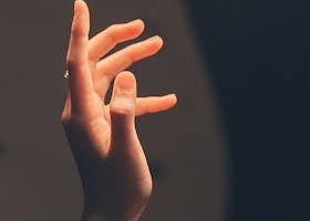Elegant human hand reaching into soft, warm light creating a serene and artistic effect.